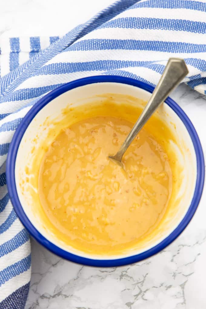 peanut sauce in a blue and white bowl with a spoon on a marble countertop 