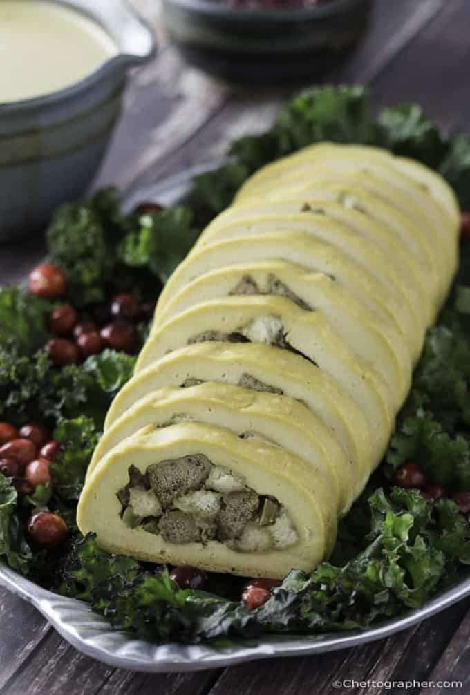 vegan turkey roll on a bed of kale and cranberries with gravy in the background 