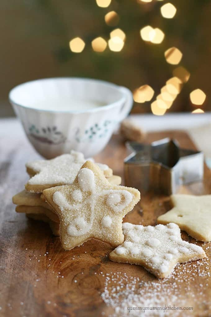 vegan sugar cookies on a wooden board with a cookie cutter and a mug in the background 