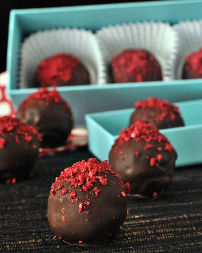chocolate truffles with raspberry topping in a blue box with some more truffles on the side 