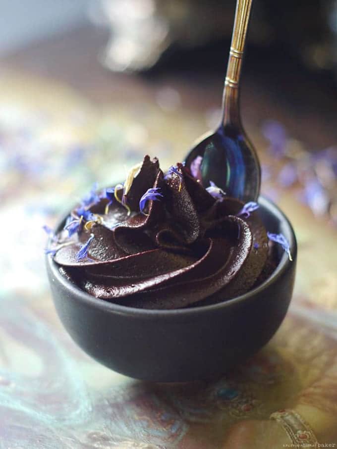 vegan espresso chocolate mousse in a small black bowl with a spoon on a wooden board 