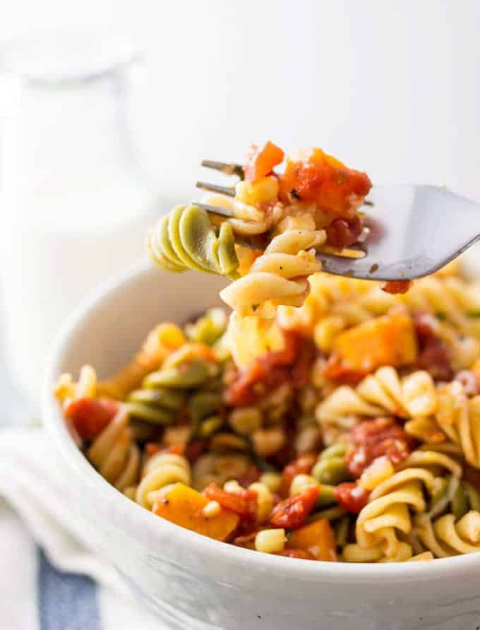 a fork picking up some pasta out of a white bowl of habanero sweet potato pasta 