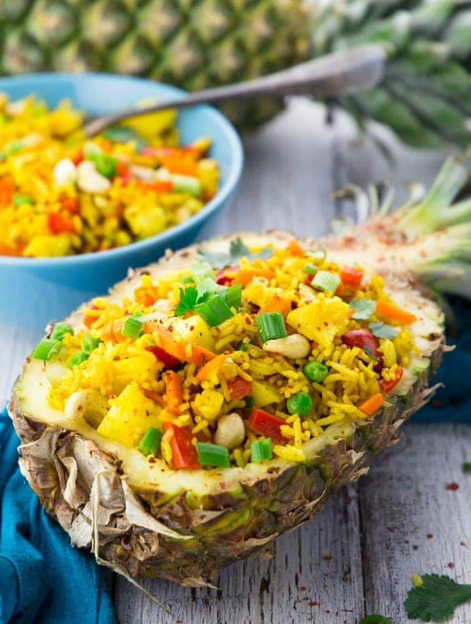 Thai pineapple fried rice in a pineapple shell with another pineapple in the background