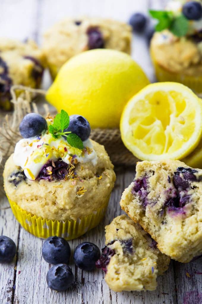 vegan blueberry muffins on a white wooden board with lemons and blueberries on the side 