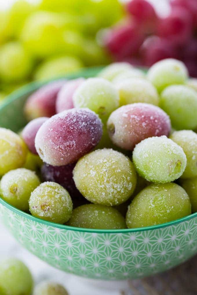 frozen grapes in a green bowl on a marble counter top 