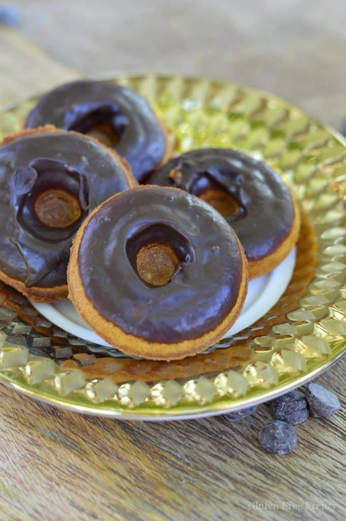 four vegan pumpkin donuts on a golden plate on a wooden surface