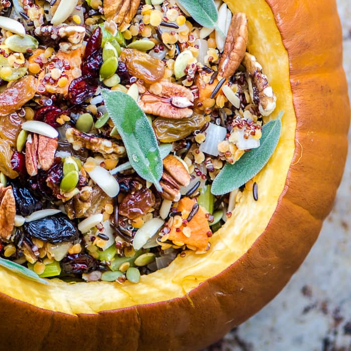 a stuffed pumpkin with fresh leaves of sage on a marble counter top 