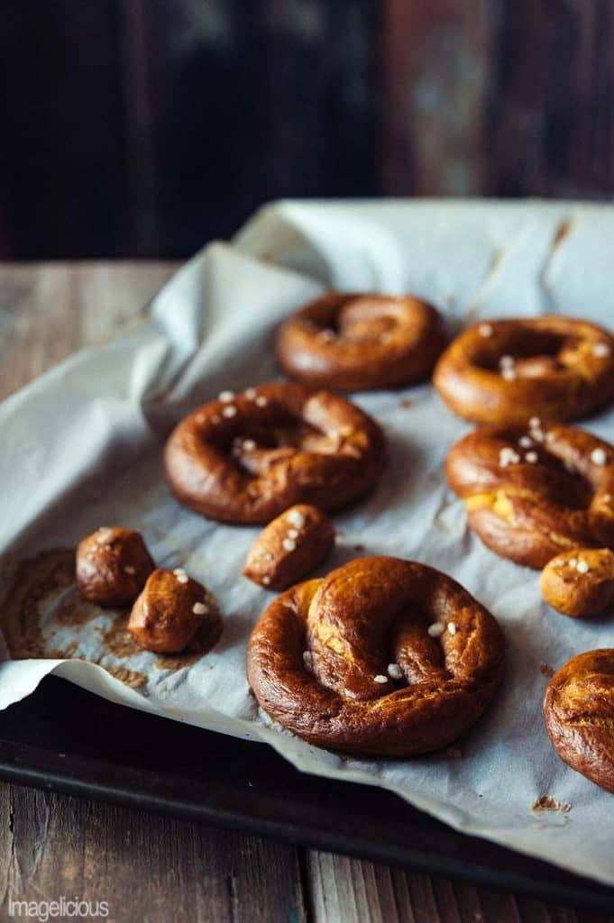 pumpkin pretzels on a baking tray lined with parchment paper and a dark background