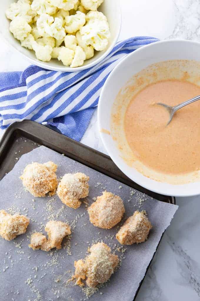 Coated cauliflower wings on a baking sheet