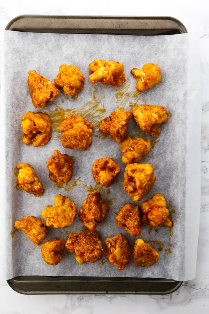 coated cauliflower hot wings on a baking sheet lined with parchment paper (before baking) 