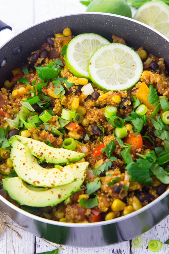 One pan Mexican quinoa in a black pot with avocado and lime slices on top 