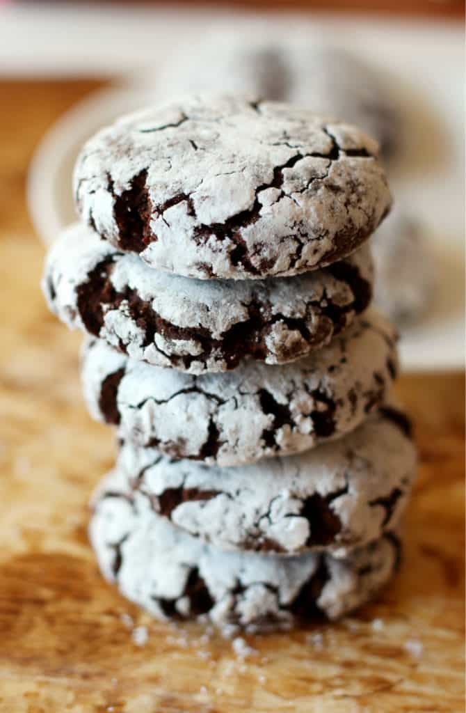 a stack of chocolate peppermint crinkle cookies on a wooden board 