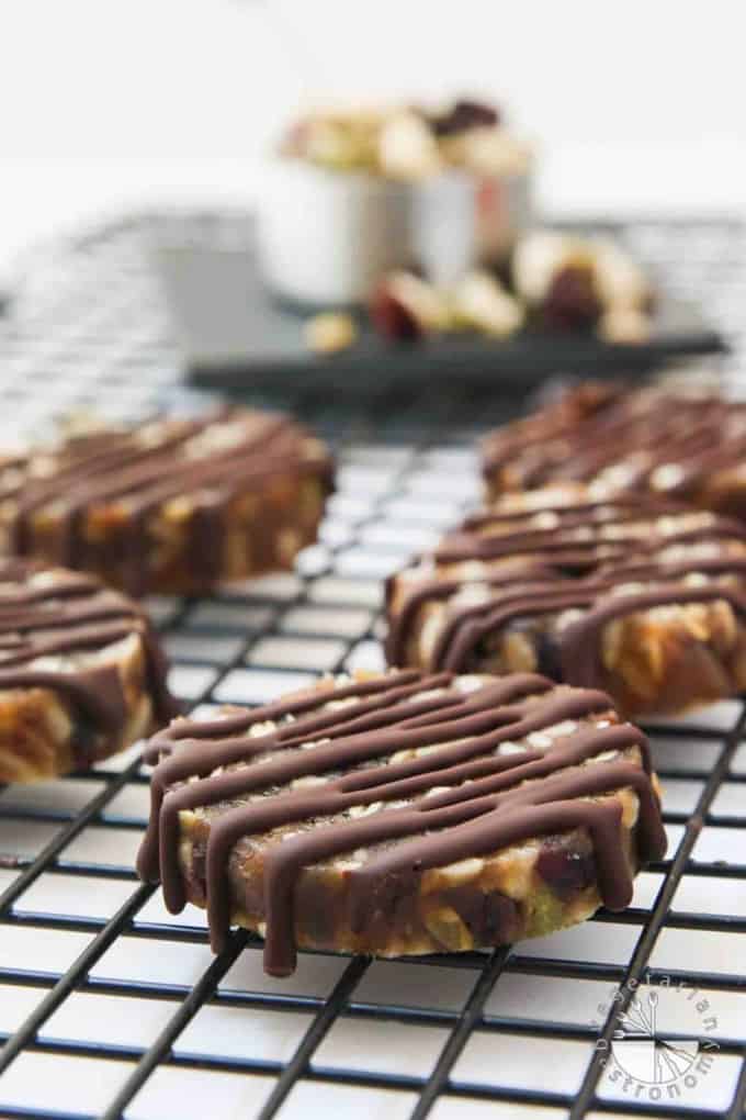 no bake chocolate date cookies on a cooling rack with a bowl of dried fruits and nuts in the background