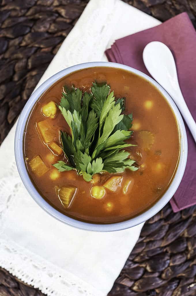 vegan harira soup in a white bowl on top pf a white and a pink napkin with a little white spoon on the side 