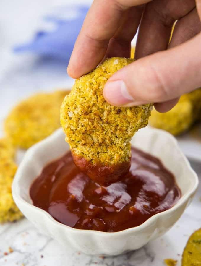 A Vegan Chicken Nugget is Being Dipped into a Small Bowl of Ketchup 