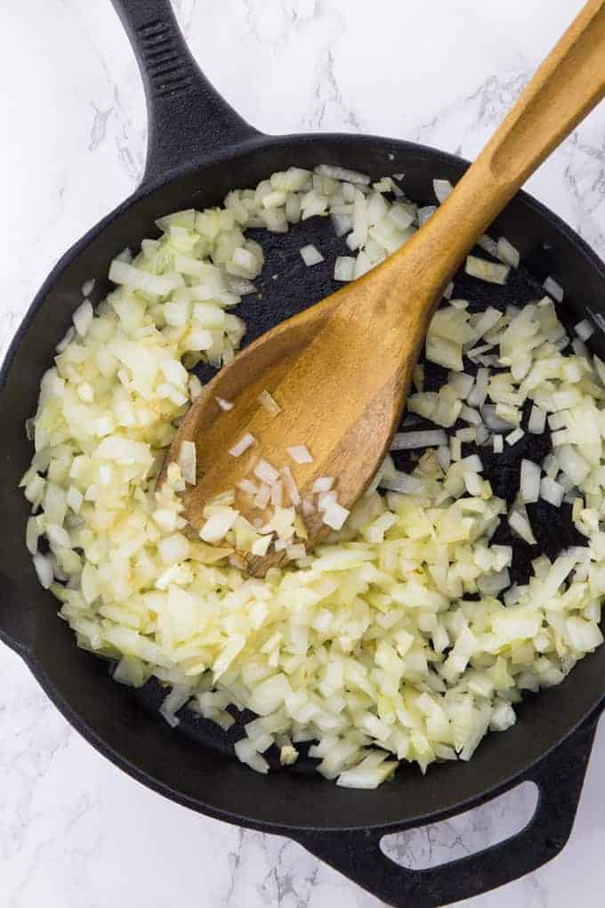 sauteed onions in a cast iron pan with a wooden spoon