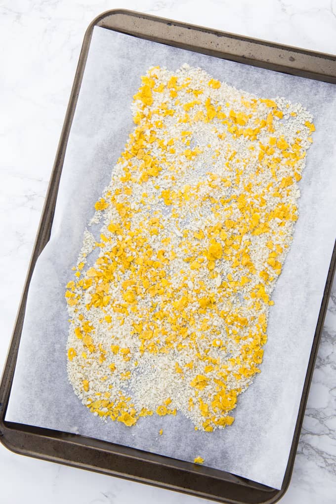 crumbled cornflakes and panko breadcrumbs on a baking sheet lined with parchment paper
