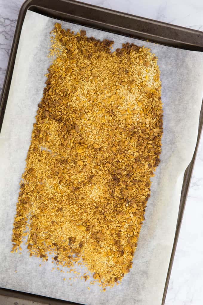Baked cornflakes and panko breadcrumbs on a baking sheet lined with parchment paper