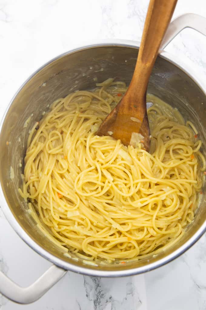 Lemon Spaghetti in a pot with a wooden spoon on a marble countertop 