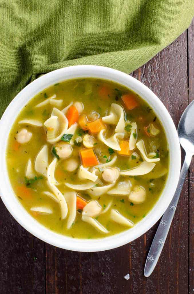 Bowl with a chickpea noodle soup with a spoon and a green napkin