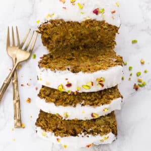 three slices of vegan carrot cake on a marble countertop with two forks on the side