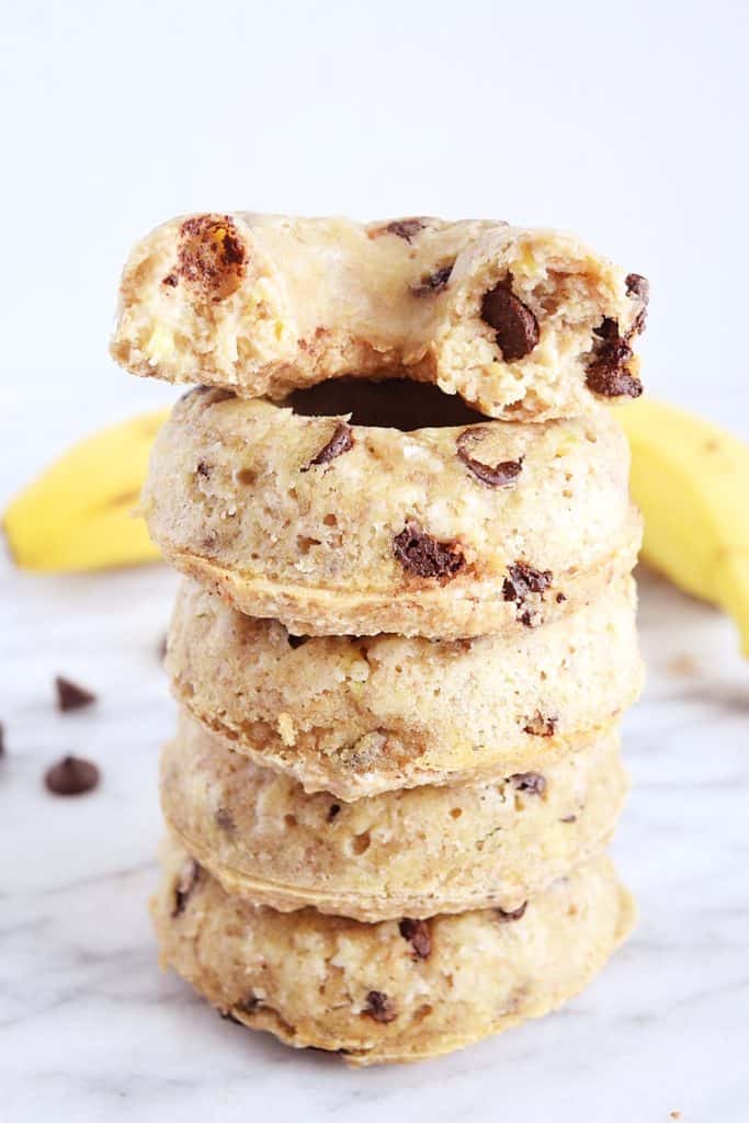 a stack of five vegan banana donuts on a marble counter top with a banana in the background 