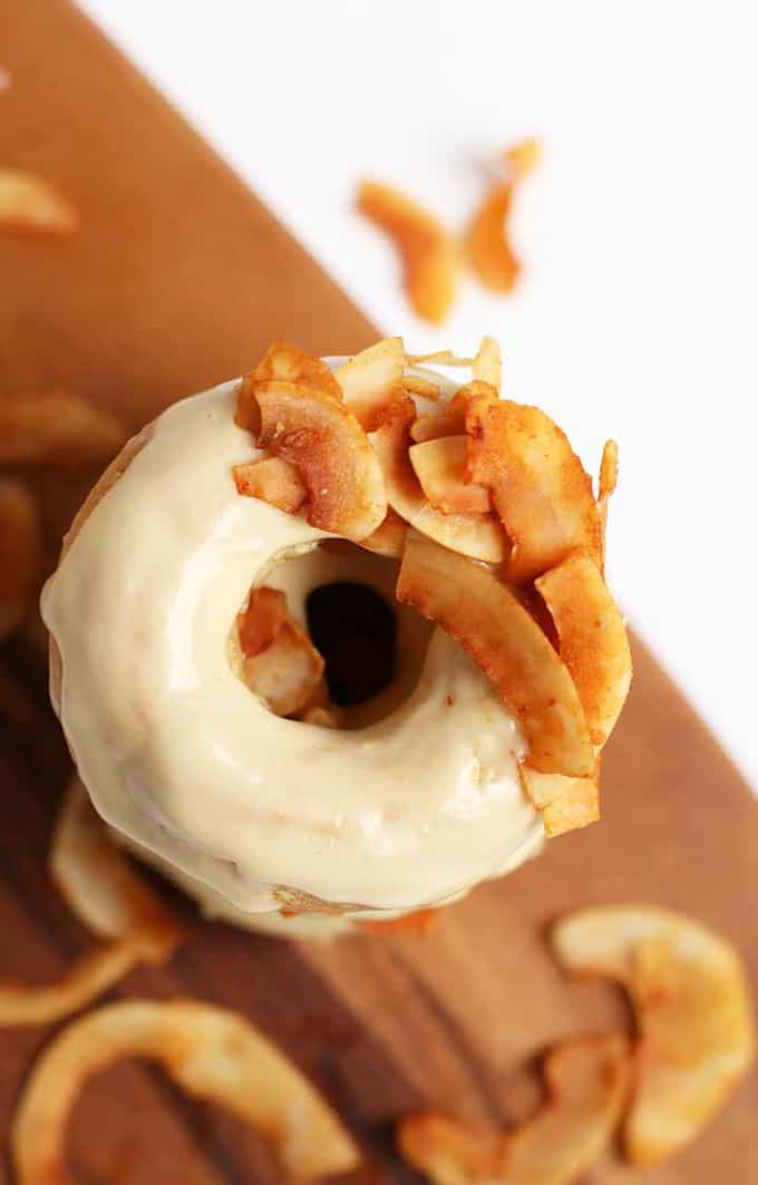 a stack of vegan donuts with coconut bacon on a wooden board with more coconut bacon on the side 