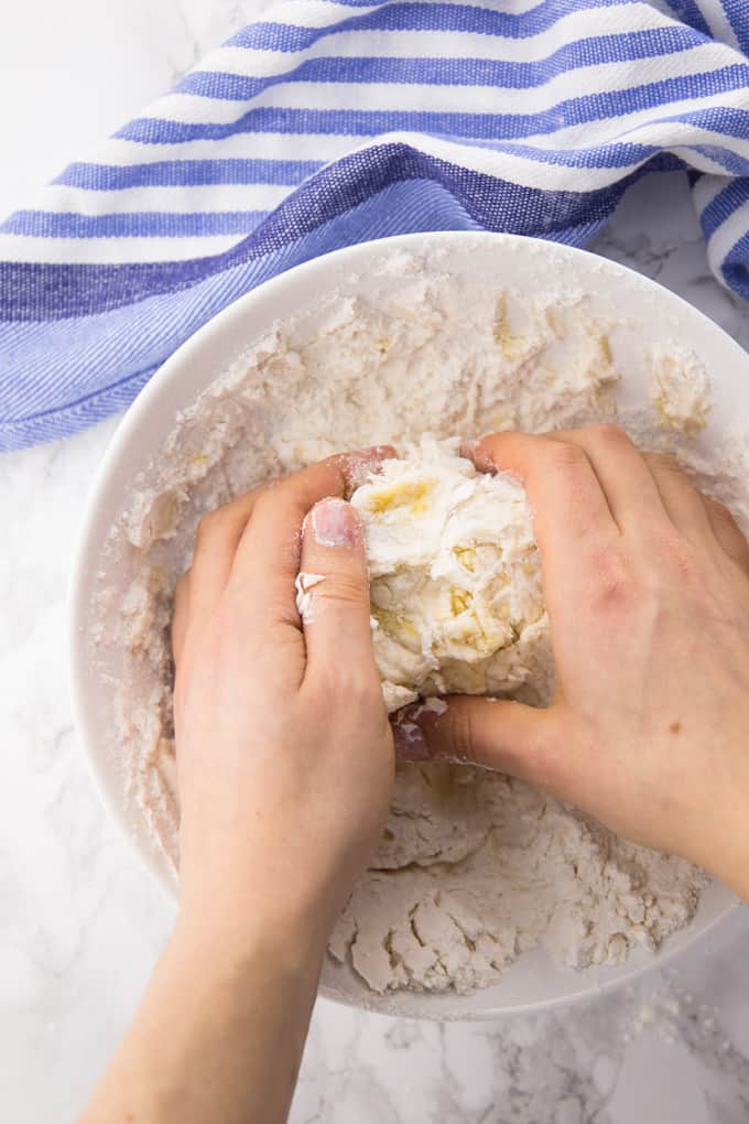 Hands kneading pizza dough in a bowl