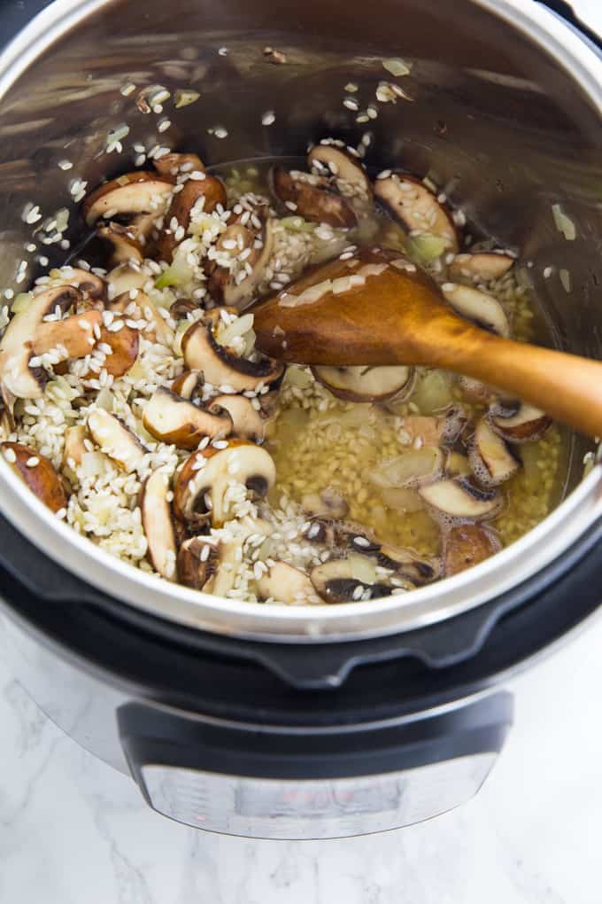 Mushrooms and aborio rice are being deglazed with white wine in an instant pot