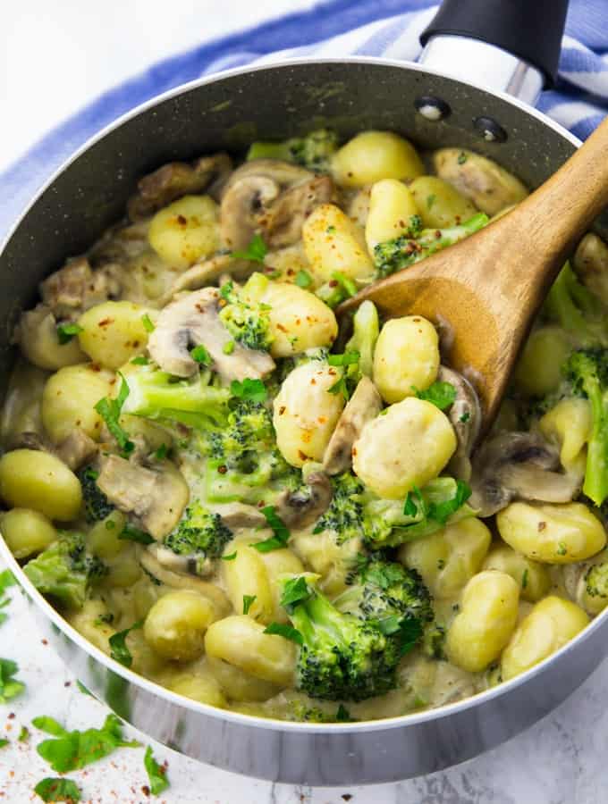 Mushroom gnocchi with broccoli in a pot with a wooden spoon
