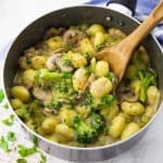 vegan gnocchi with mushrooms and broccoli in a pot with a wooden spoon