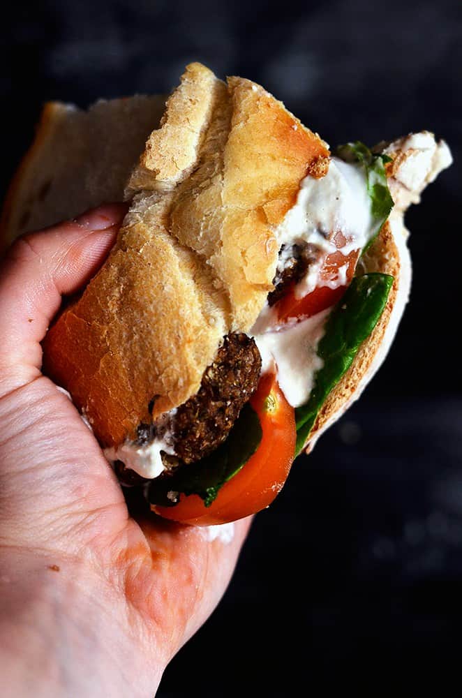 A Hand Holding A Mushroom Meatball & Garlic Cream Sandwich 