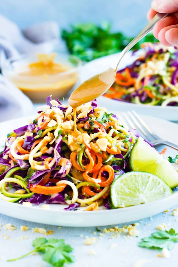 Sauce Being Poured Over A Thai Zucchini Noodle Salad with Cabbage 