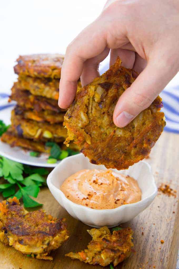 Vegetable Potato Fritters Being Dipped in Sauce 