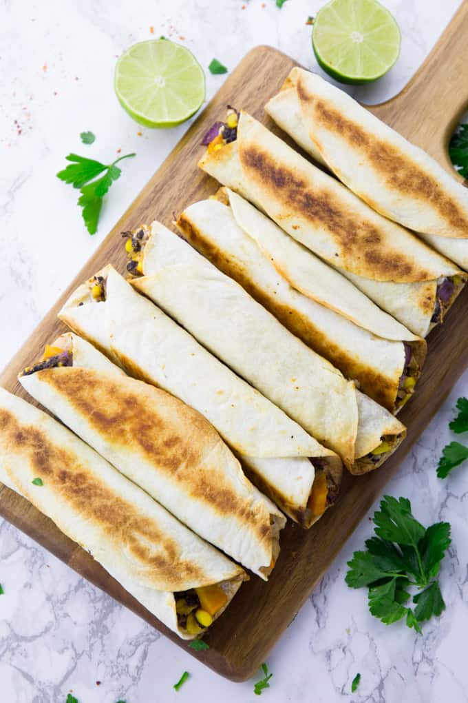 freshly baked taquitos on a wooden board 