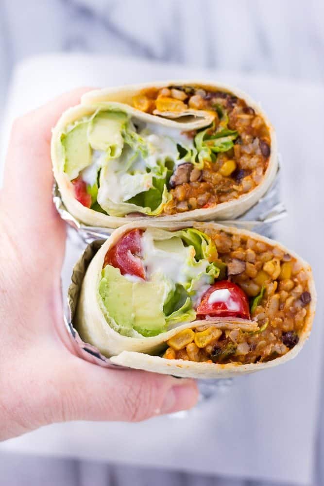 A Hand Holding Two Vegan Burritos