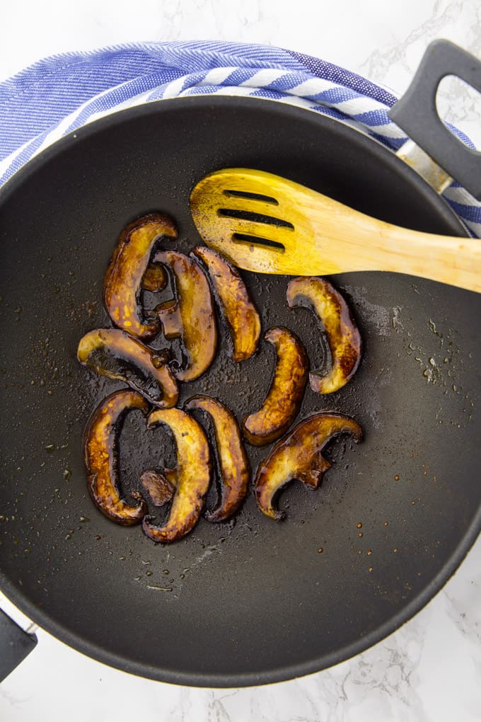 Vegan mushroom bacon in a pan with a wooden wooden spoon