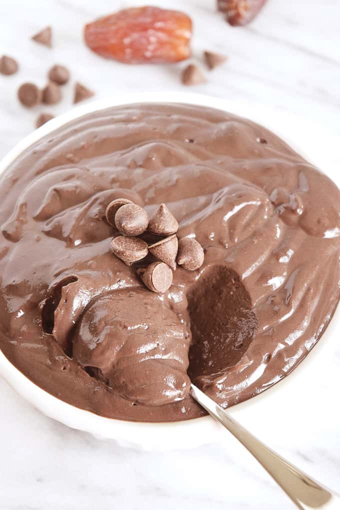 Vegan Chocolate Pudding on a white counter top with a spoon