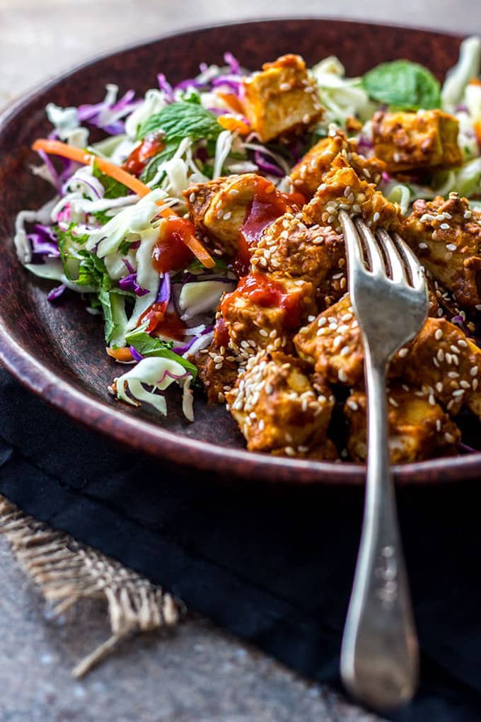 Baked Spicy Peanut Butter Tofu in Dark Bowl with a Fork