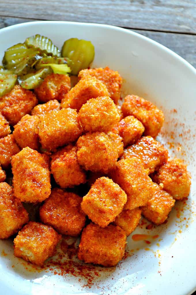 Nashville Hot Tofu Nuggets in a white bowl with pickles on one side