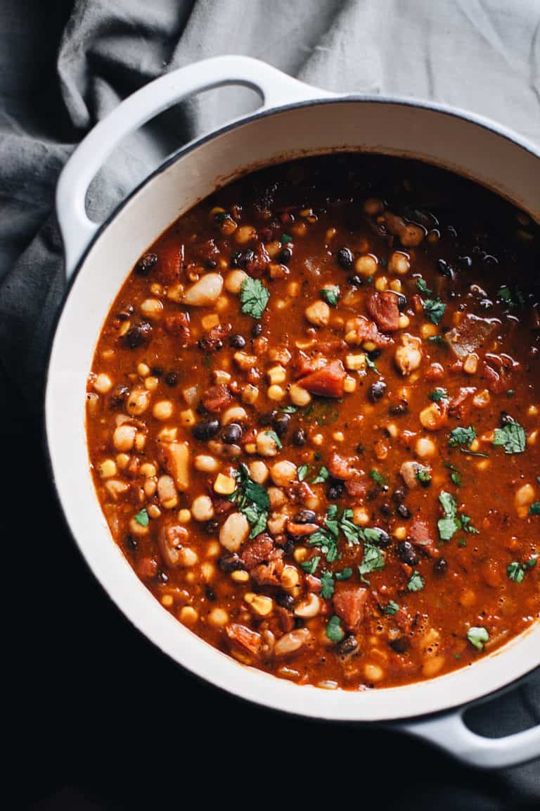 A large pot of vegan chili on a dark surface with a grey napkin in the background