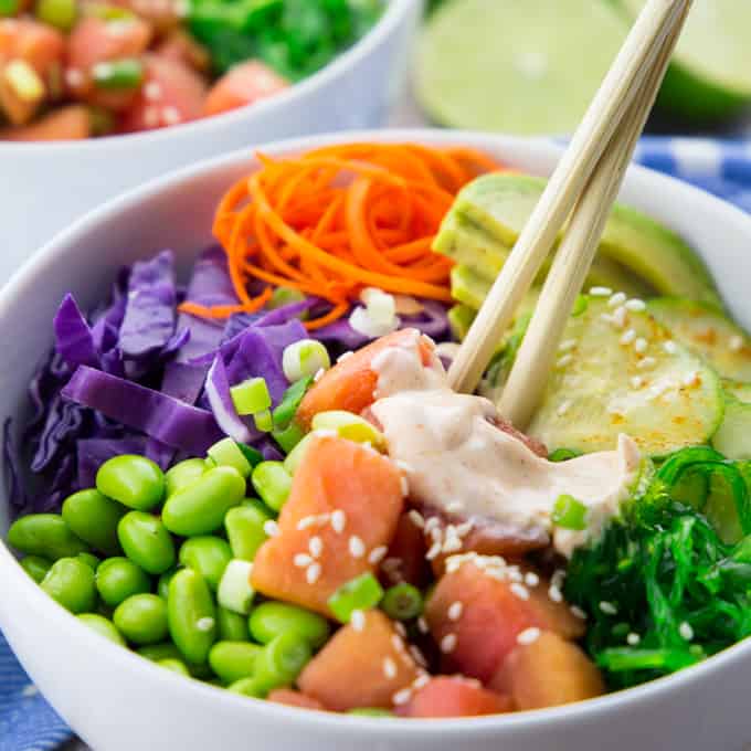 a vegan poke bowl with chop sticks and lime halves in the background