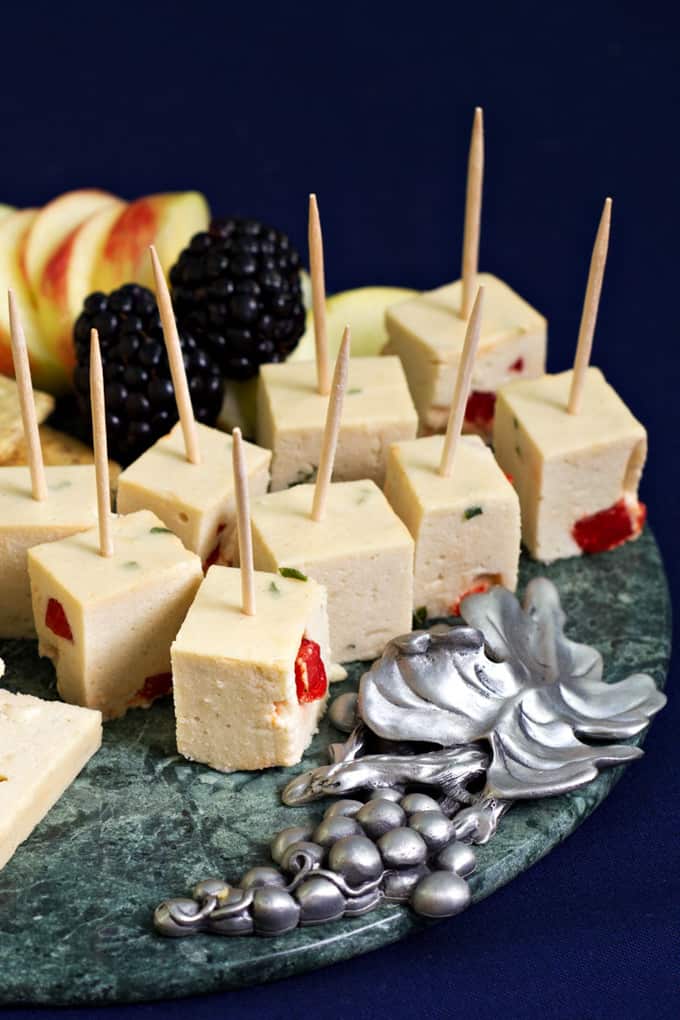 vegan cheeze cubes with toothpicks on a metal plate with a black background