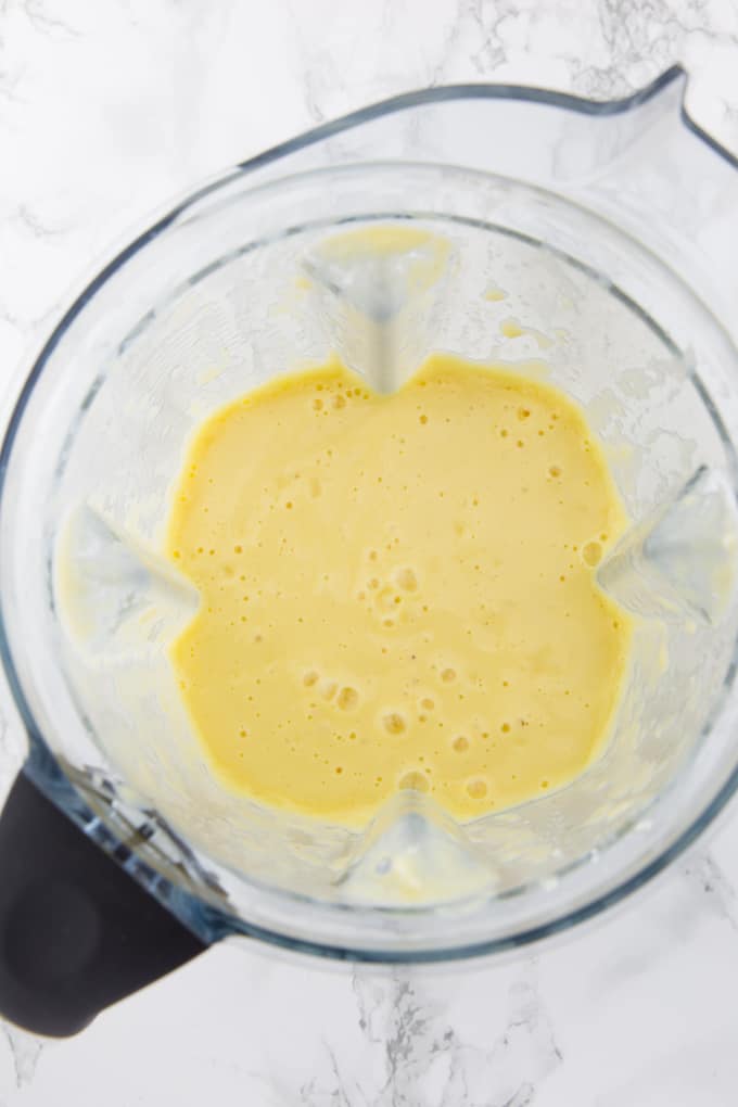 Mango Smoothie in a blender on a marble countertop 