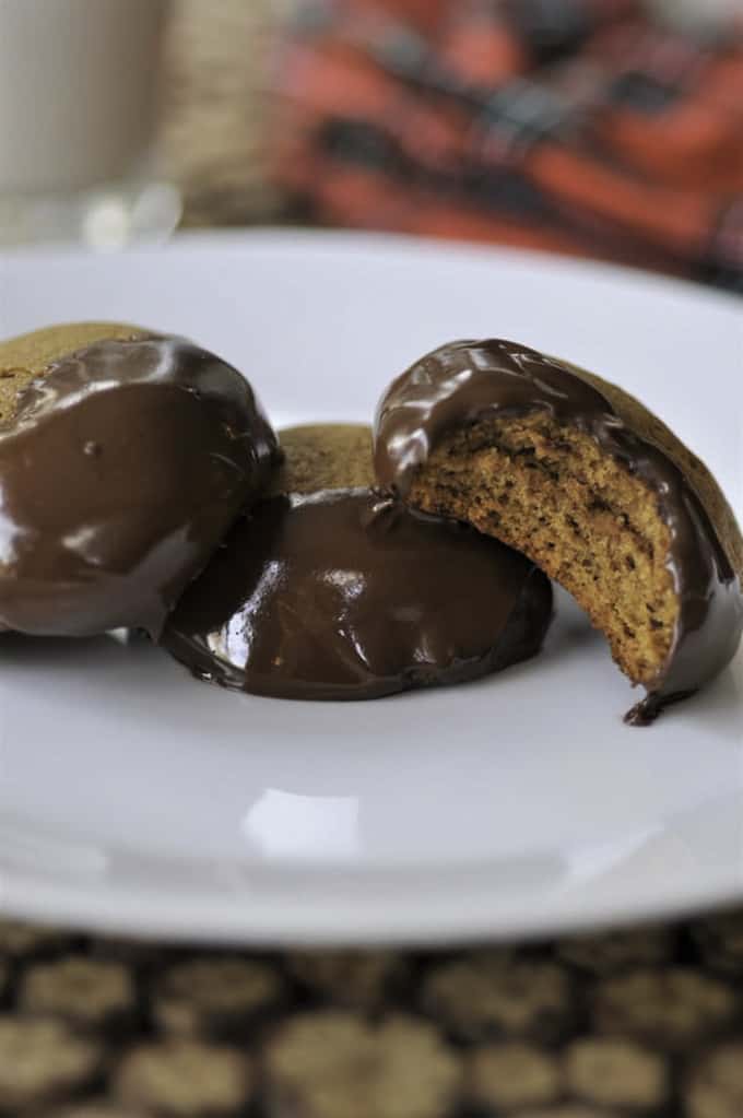 Three . Chocolate Dipped Ginger Cookies on a white plate with a red dish cloth in the background