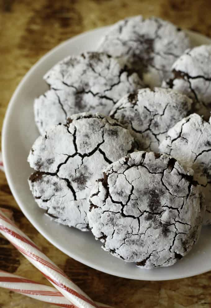 . Chocolate Peppermint Crinkle Cookies on a white plate with two candy canes on the side
