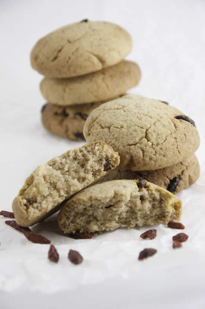 two stacks of Vegan Ginger Goji Cookies on a white surface with some goji berries on the side