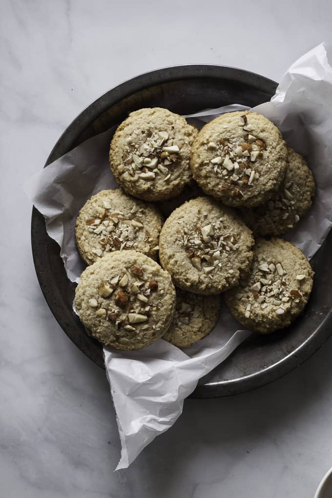 Gluten-Free Maple Almond Cookies in a dark bowl with parchment paper on marble counter top