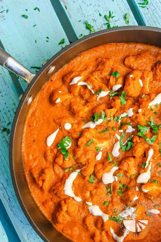 Cauliflower Tikka Masala in a pan on a blue wooden board 