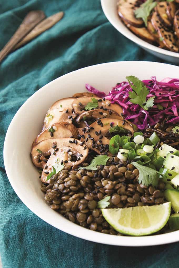 Two Marinated Mushroom Bowls in white bowls on a greenish-blue table cloth 